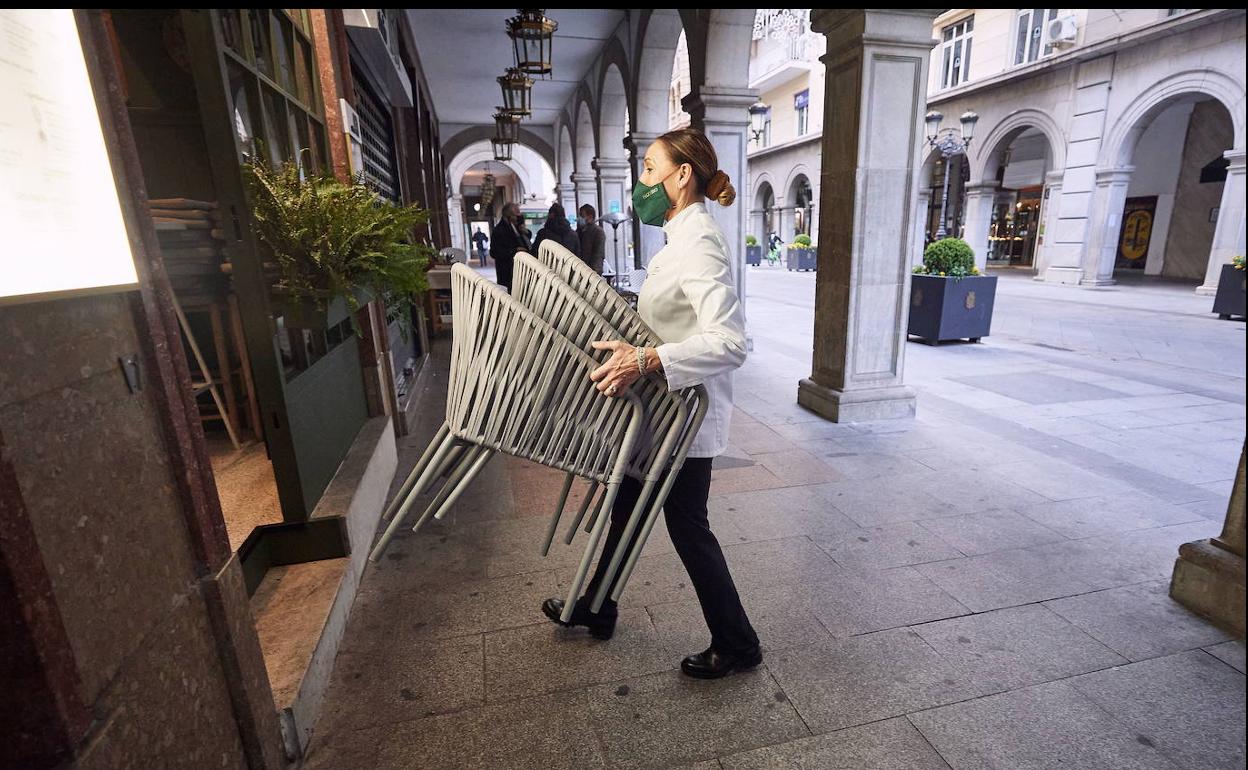 Una mujer recoge las sillas de su terraza en Granada, en una foto de archivo.