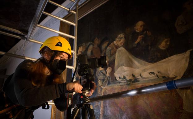 Tomando fotografías del lienzo desde lo alto del andamio colocado en el Salón Rojo. 