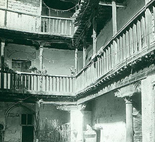 Patio de una casa con planta baja y dos pisos con corredor, vigas, pilares y balconadas de madera, característica del Albaicín. 