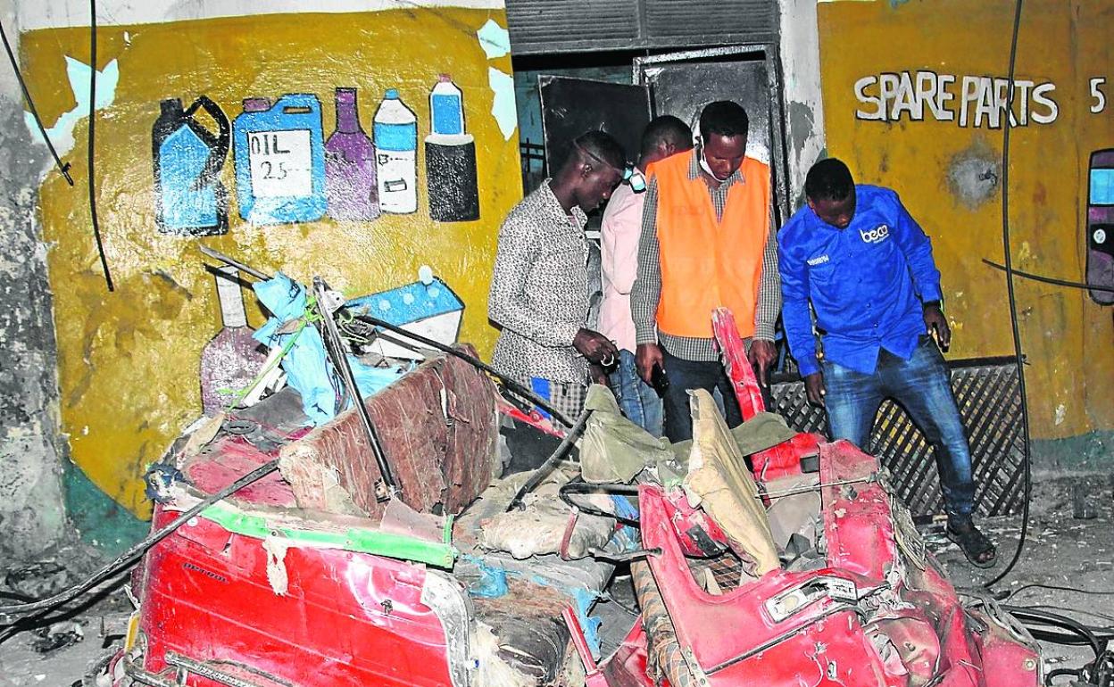 Varios jóvenes examinan los restos de un vehículo cargado de explosivos detonado en Mogadiscio.