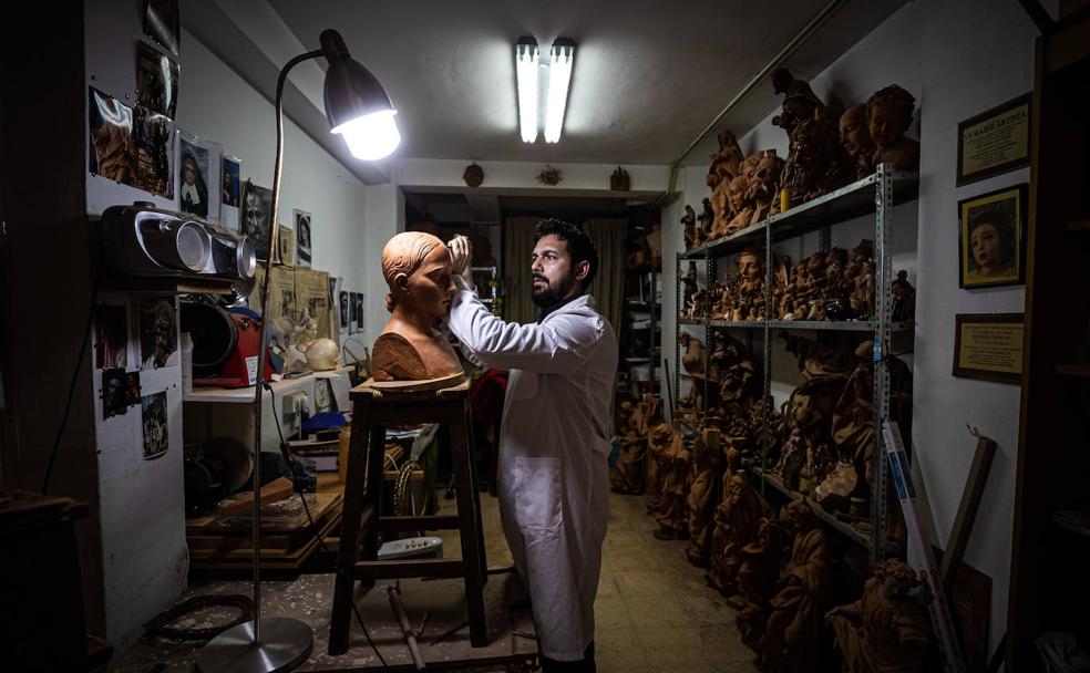 Ángel Asenjo trabaja, gubia y maza en mano, en el boceto de una dolorosa en barro. Se trata de un estudio previo a lo que será la pieza definitiva. 