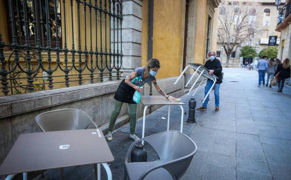 Dos camareros recogen las mesas de la terraza del Bar de Eric.