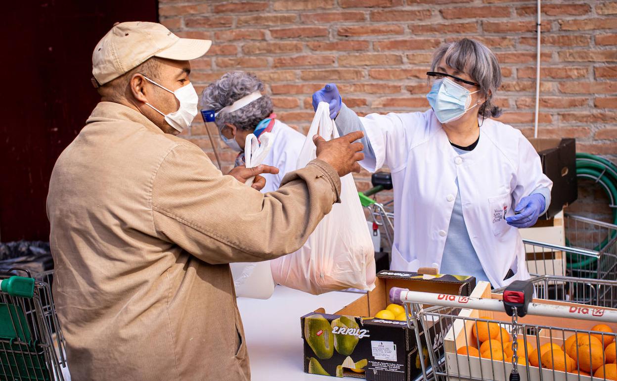 Una voluntaria entrega frutas en la cola del hambre.