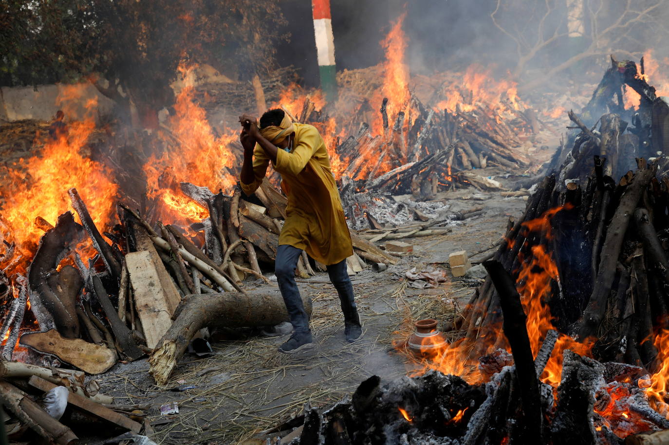 Un hombre camina entre las piras funerarias en India.