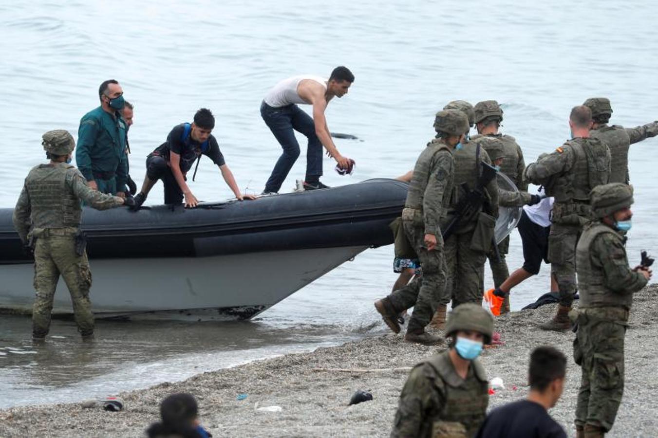 Legionarios españoles y ciudadanos marroquíes en la playa El Tarajal, cerca de la valla entre la frontera hispano-marroquí.