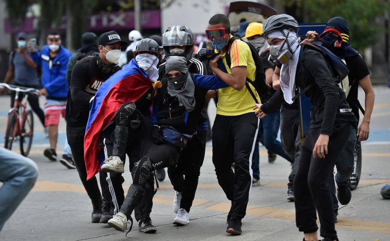 Un grupo de hombres ayuda a otro tras ser alcanzado por una bala durante enfrentamientos contra la Policía. 