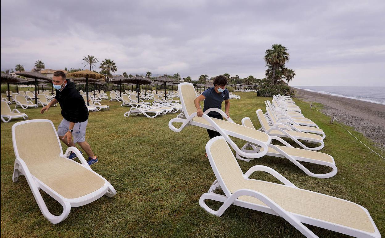Los trabajadores del hotel de Playa Granada colocan las hamacas frente a la orilla. 