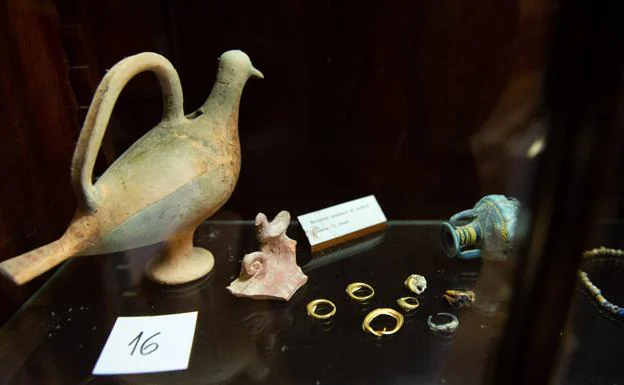 Vaso zoomorfo de tradición fenicia representando una paloma junto a pendientes de oro y a una pequeña ánfora de pasta vítrea. 