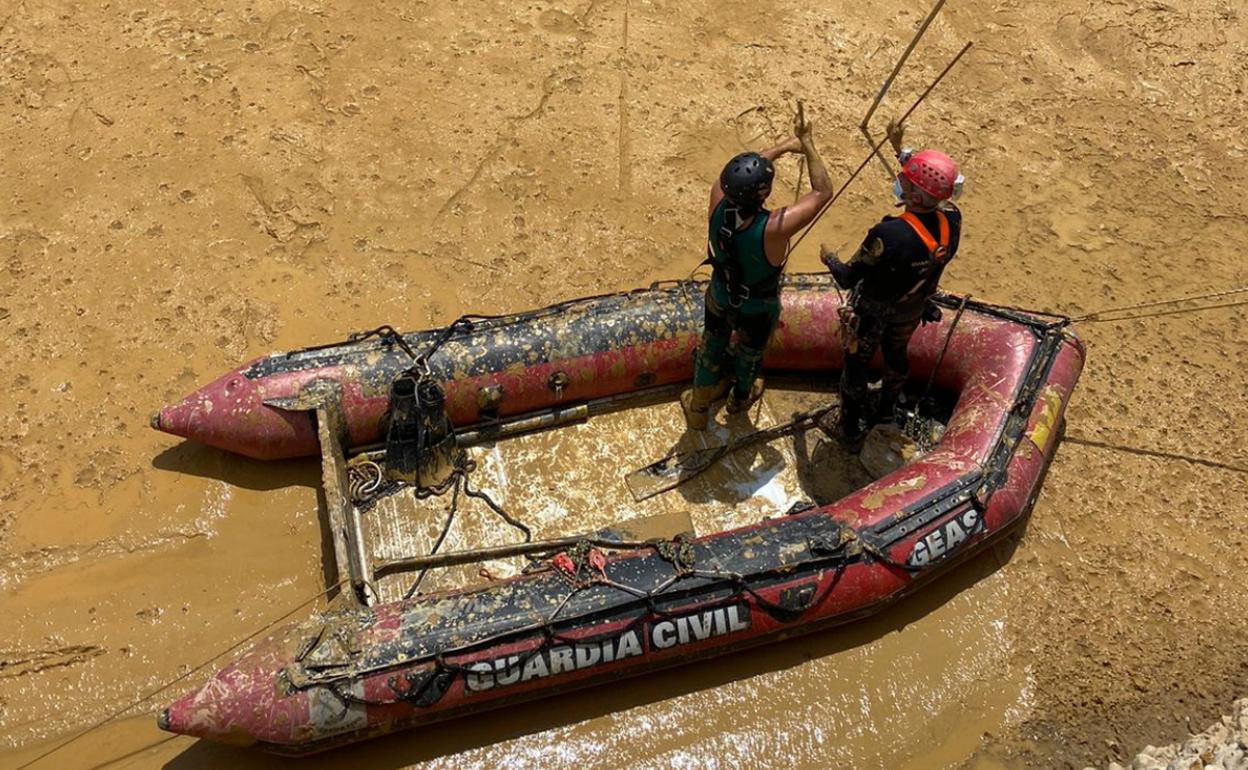 Agentes del GEAS buscando con pértigas el lugar en el que se haya la retroexcavadora.