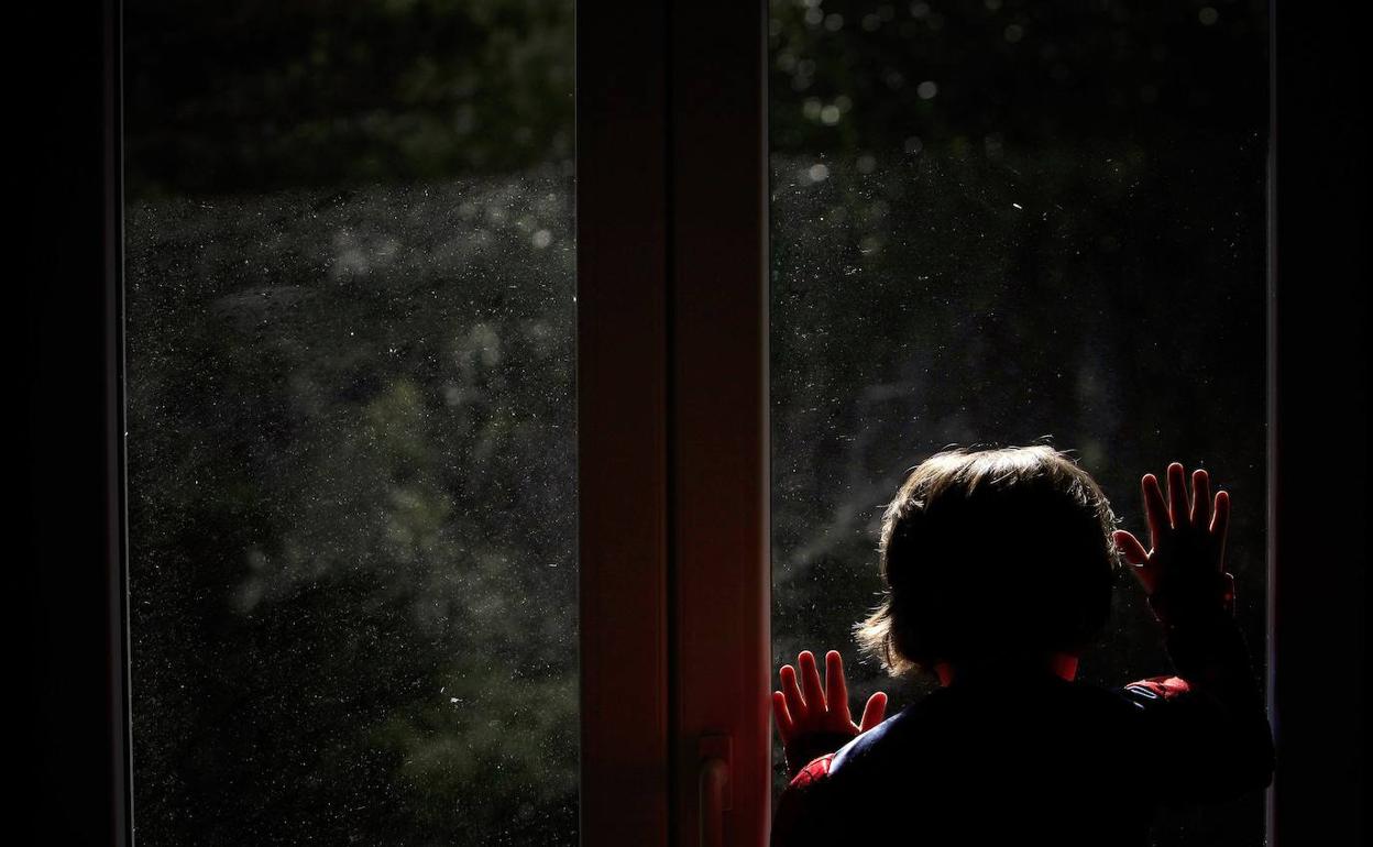 Una mujer confinada observa la calle desde su ventana.