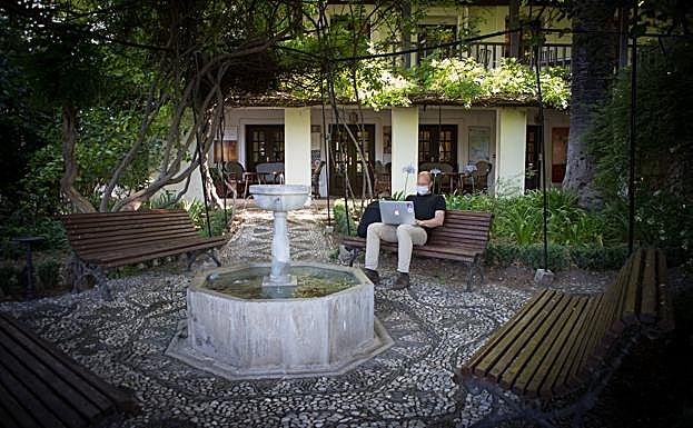 Un huésped trabaja con su ordenador en el jardín. 