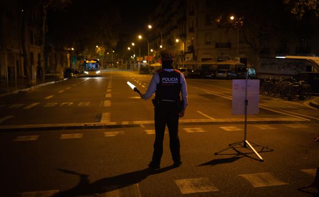 Un mosso colabora en un control durante el toque de queda impuesto en Barcelona. 