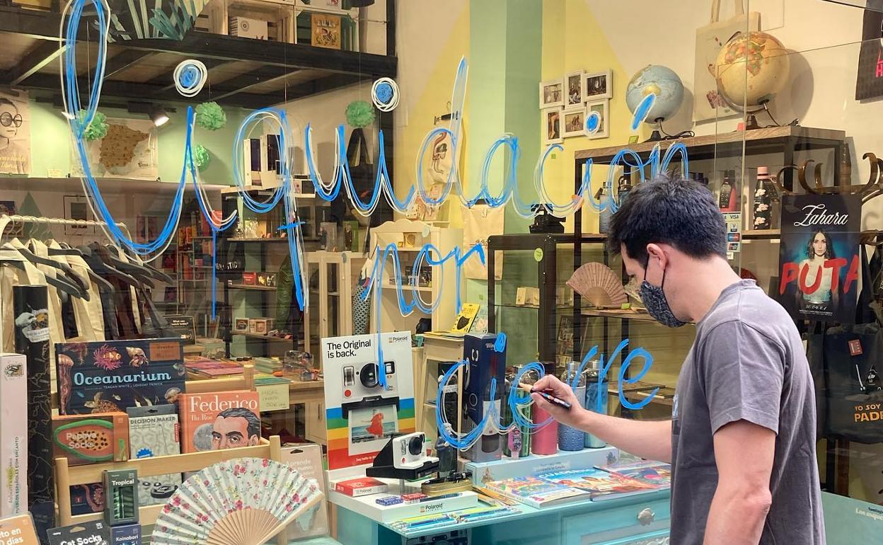 Miguel pintando el escaparate de la tienda con el mensaje de liquidación.