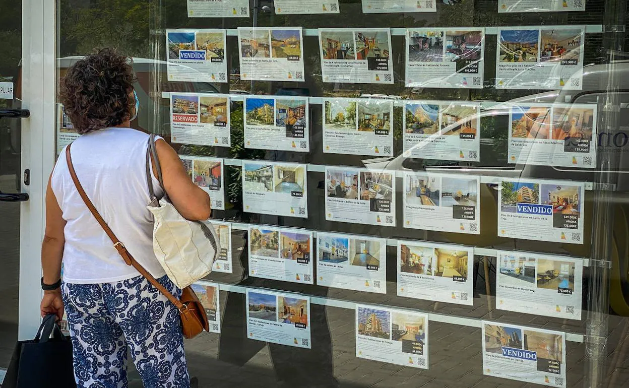 Una mujer observa las ofertas disponibles en la cristalera de una inmobiliaria en la capital granadina. 