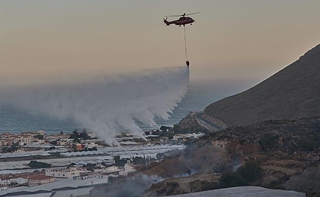 Un helicóptero arroja llamas sobre el fuego.