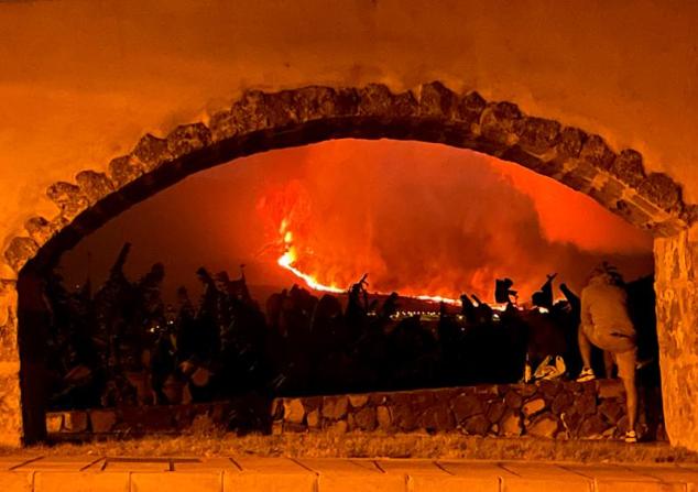 Un hombre mira la lava y el humo que se eleva desde el volcán.