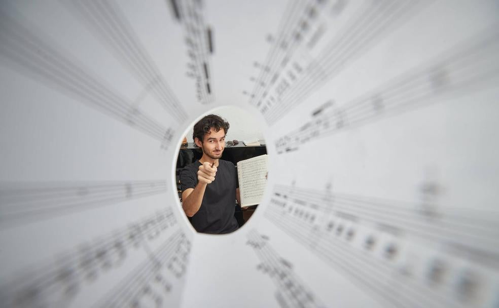 El compositor Pedro Osuna, sentado junto al piano de su casa y rodeado por una partitura. 