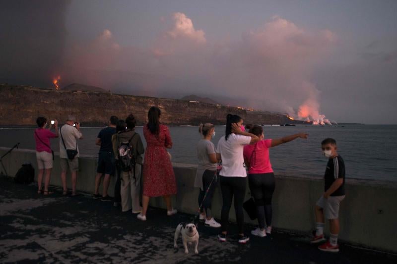 Varias persona observan el volcán de Cumbre Vieja y la fajana de lava desde el puerto de Tazacorte.
