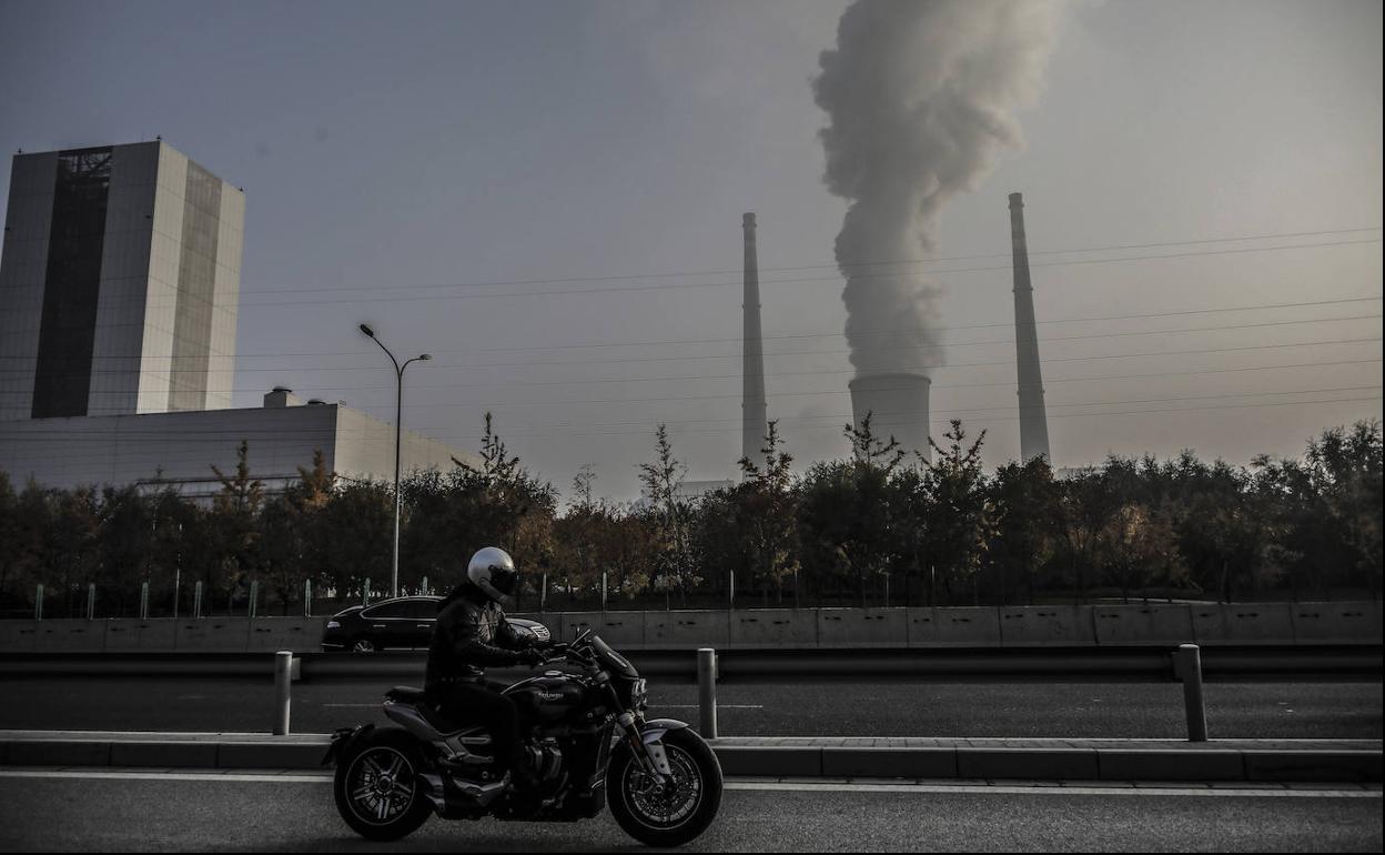 Una moto de lujo y gran cilindrada circula junto a las instalaciones de una central termoeléctrica de carbón. 