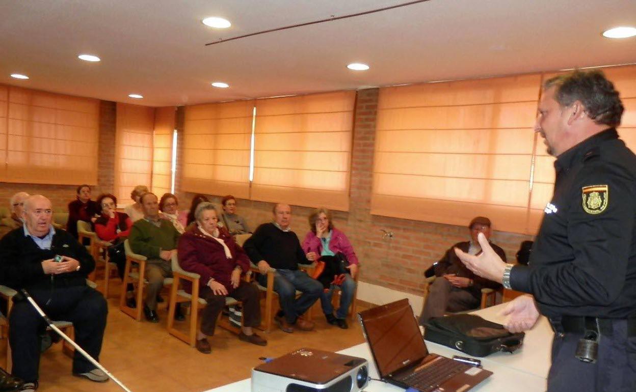 Un policía nacional informa a un grupo de mayores sobre las estafas.