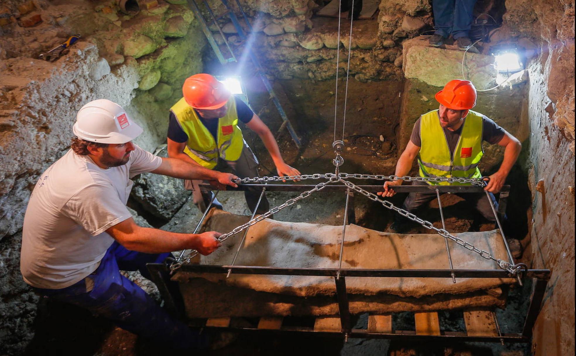 Operarios levantan el sarcófago hallado en la placeta de Villamena para ser transportado al Museo Arqueológico en el verano de 2019. 