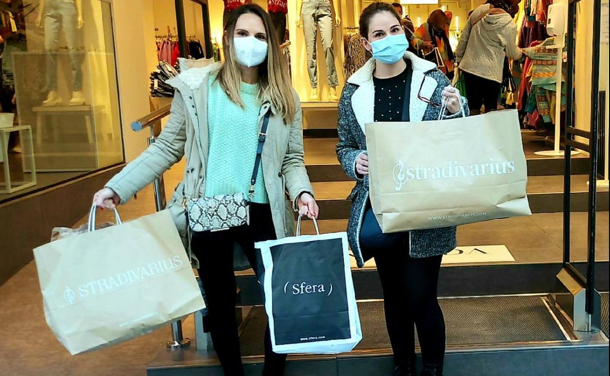 Dos jóvenes posan con sus bolsas al salir de uno de los comercios. 