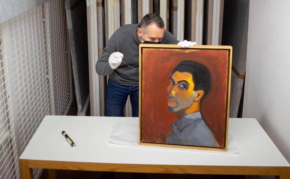 El director del Centro José Guerrero, Francisco Baena, supervisa el bastidor de 'Autorretrato', pintado por Guerrero en 1950. 