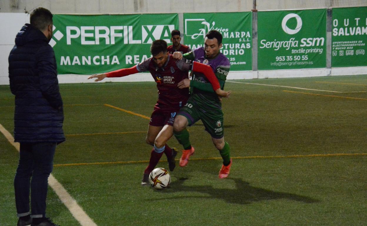 Dos jugadores del Atlético Mancha Real y Melilla luchan un balón bajo la atenta miranda de Pedro Bolaños. 