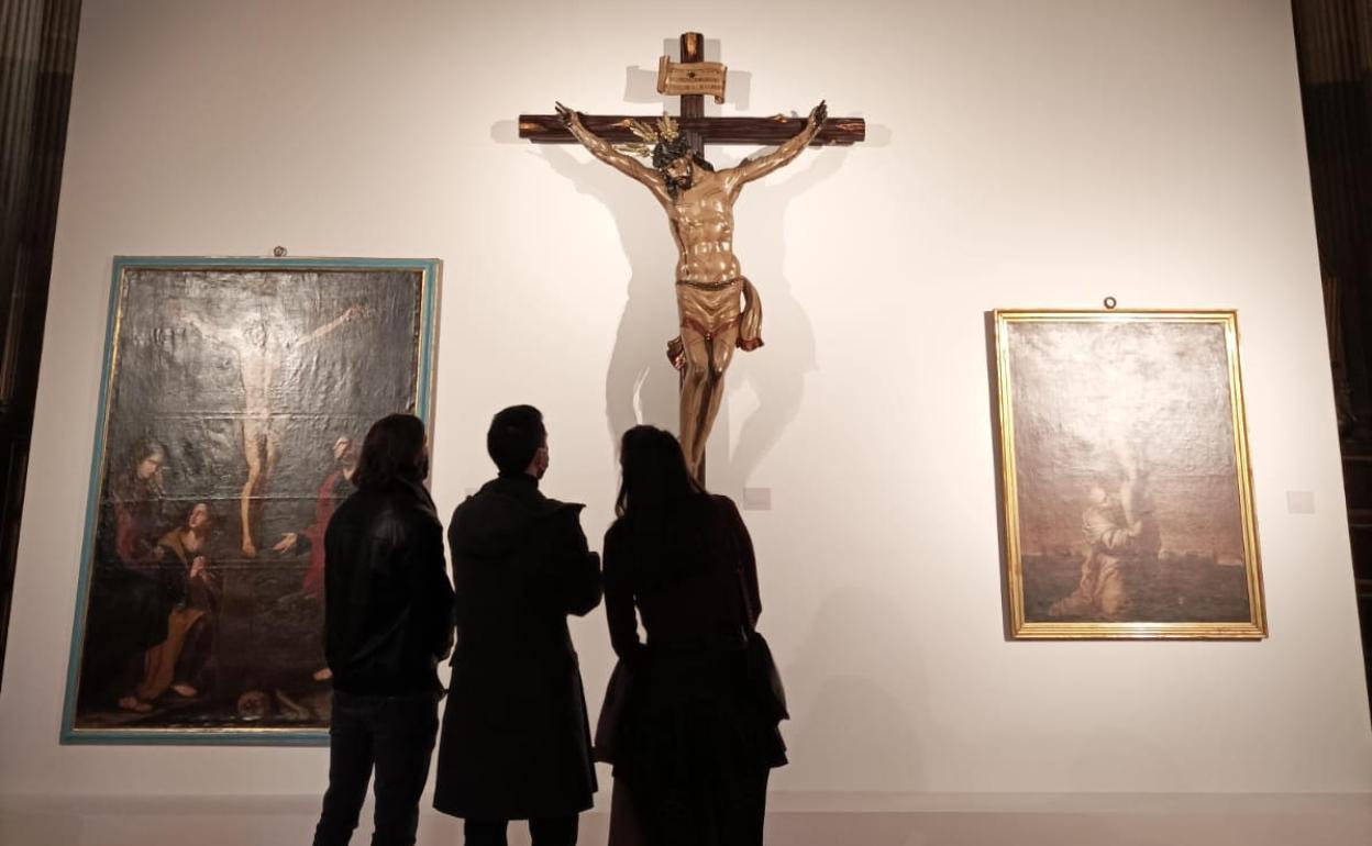 Visitantes contemplan uno de los Cristos crucificados en la exposición en la Catedral. 