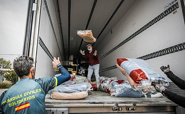 Voluntarios de la Asociación Guardias Civiles Solidarios cargan uno de los camiones con ayuda humanitaria.
