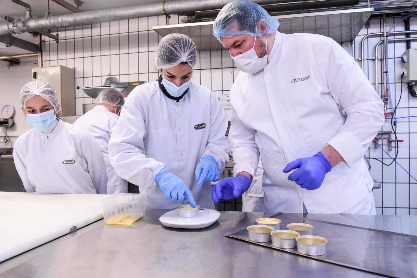 Un cocinero del equipo del chef francés Alain Ducasse (R) prepara un postre para el astronauta francés Thomas Pesquet en la fábrica de conservas Henaff en Pouldreuzic, cerca de Brest, al oeste de Francia, el 20 de abril de 2021. Pesquet embarcó en la SpaceX con destino a la Estación Espacial Internacional llevando varias comidas preparadas por el equipo de Ducasse.