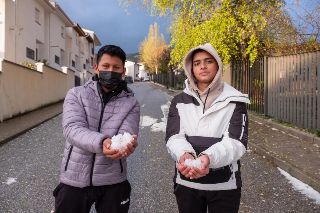 Dos jóvenes de Víznar muestran algunos restos del granizo que ha caído en la localidad.