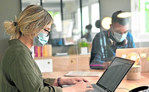 Dos trabajadores con mascarilla en su centro laboral.