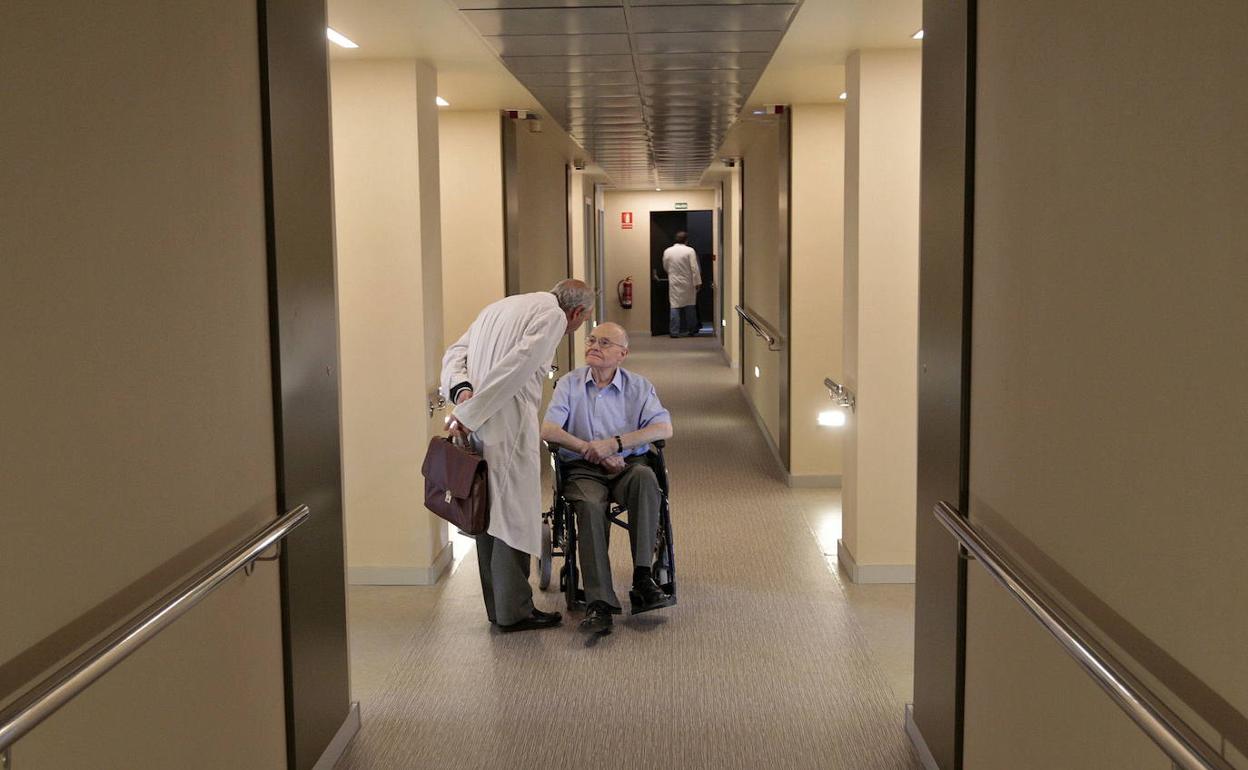 Un sanitario conversa con un paciente en un pasillo del Hospital San Rafael, en Granada.