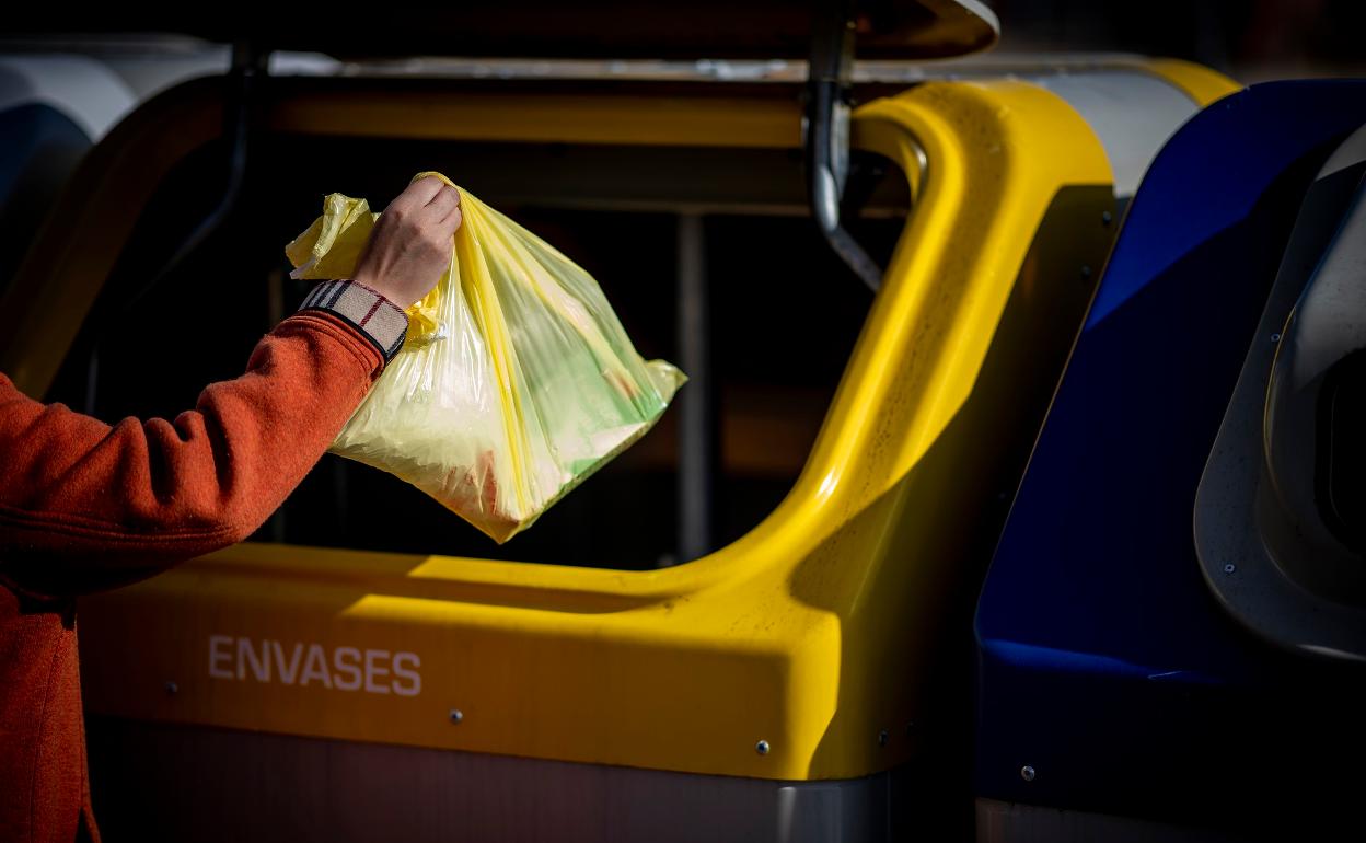 Un ciudadano deposita una bolsa de residuos en el contenedor de envases. 