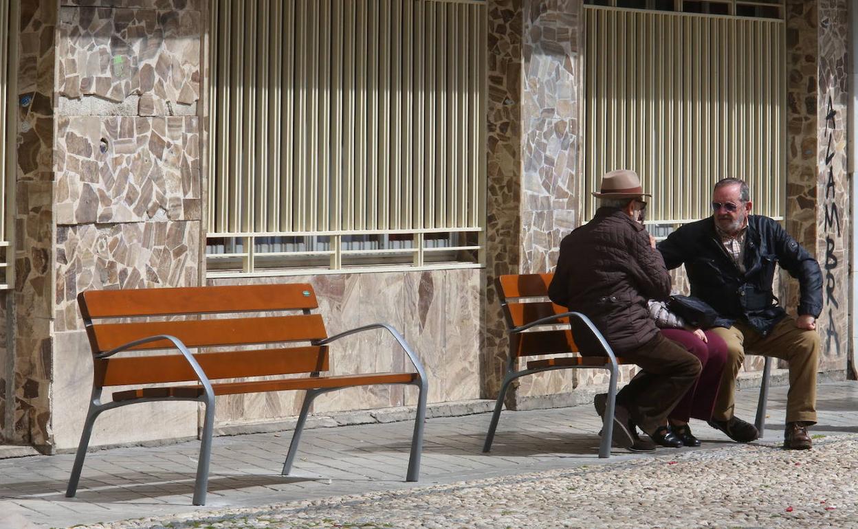 Ancianos sentados en un banco de la plaza de Gracia.