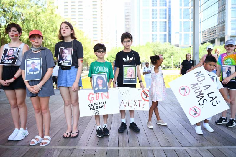 Niños con fotografías de las víctimas del tiroteo en Uvalde participan en un minuto de silencio frente a la Asociación Nacional del Rifle.