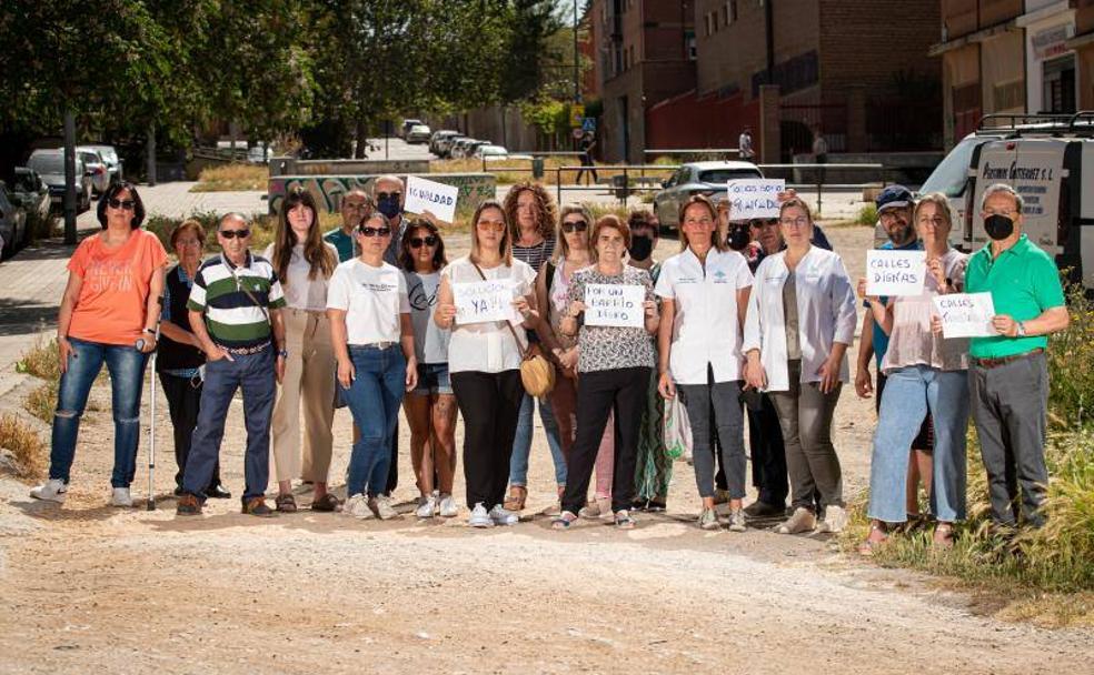 Vecinos portan carteles en una de las calles sin asfaltar. 