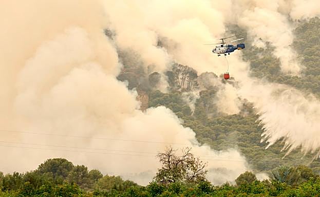 Un helicóptero vierte agua sobre una de las zonas del incendio de Mijas.