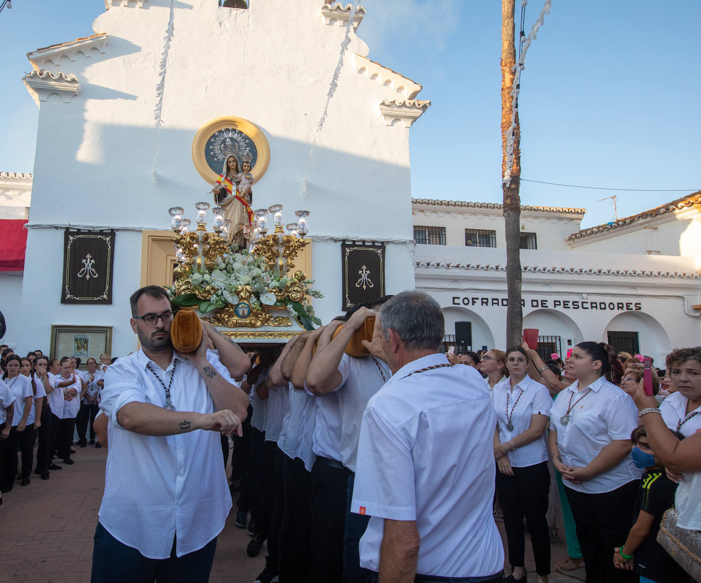 El trono de la Virgen del Carmen recibe una petalá a su paso por una de las calles de Varadero en Motril.