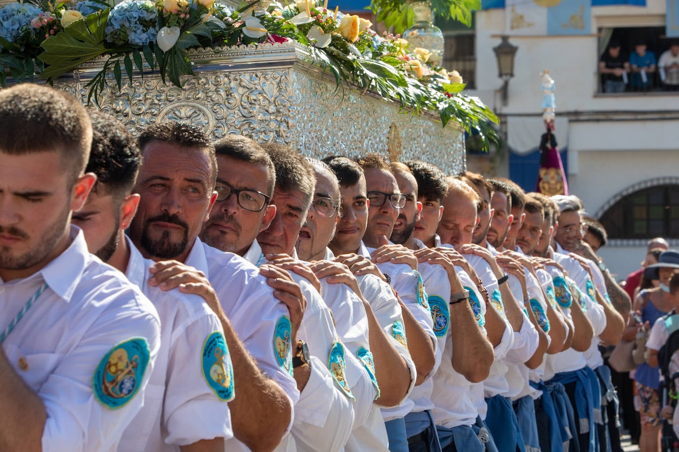 La Virgen del Carmen de Almuñéca, con el Barrio de Los Marinos al fondo, enfila la playa de San Cristóbal tras salir de la capilla.