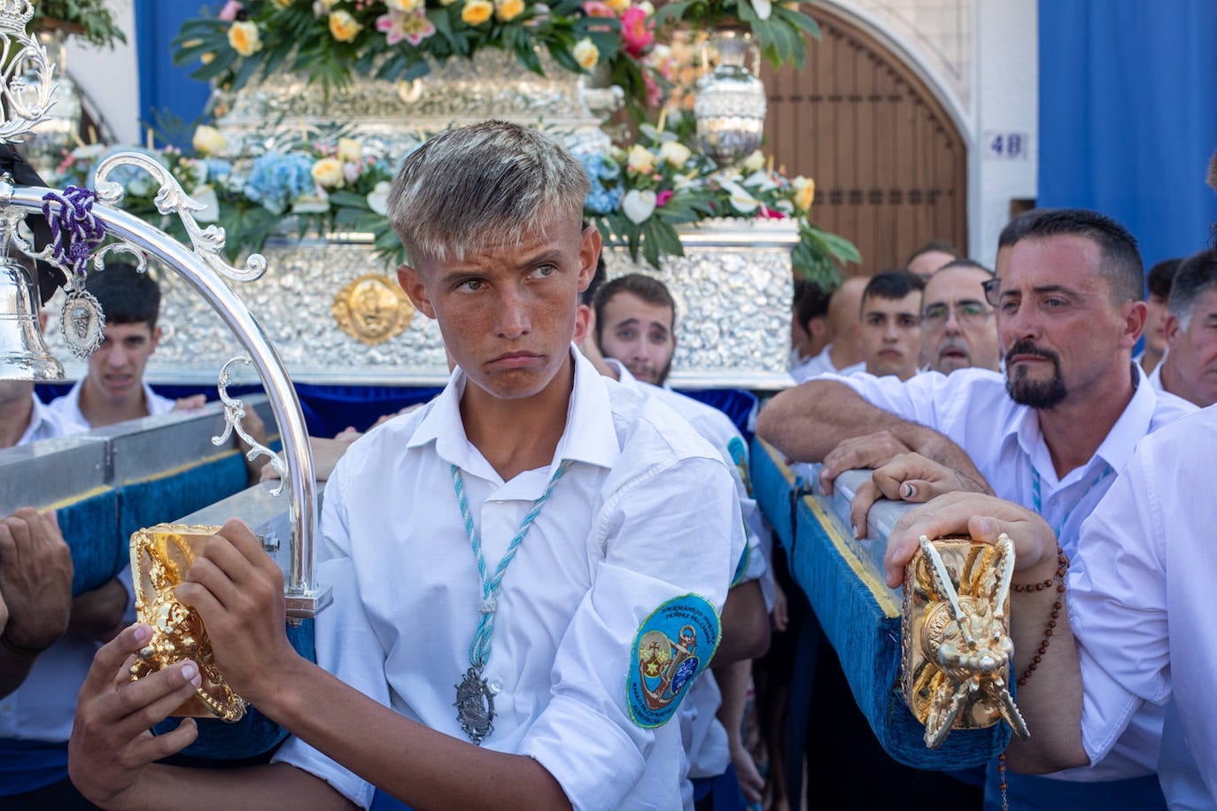 La Virgen del Carmen de Almuñéca, con el Barrio de Los Marinos al fondo, enfila la playa de San Cristóbal tras salir de la capilla.