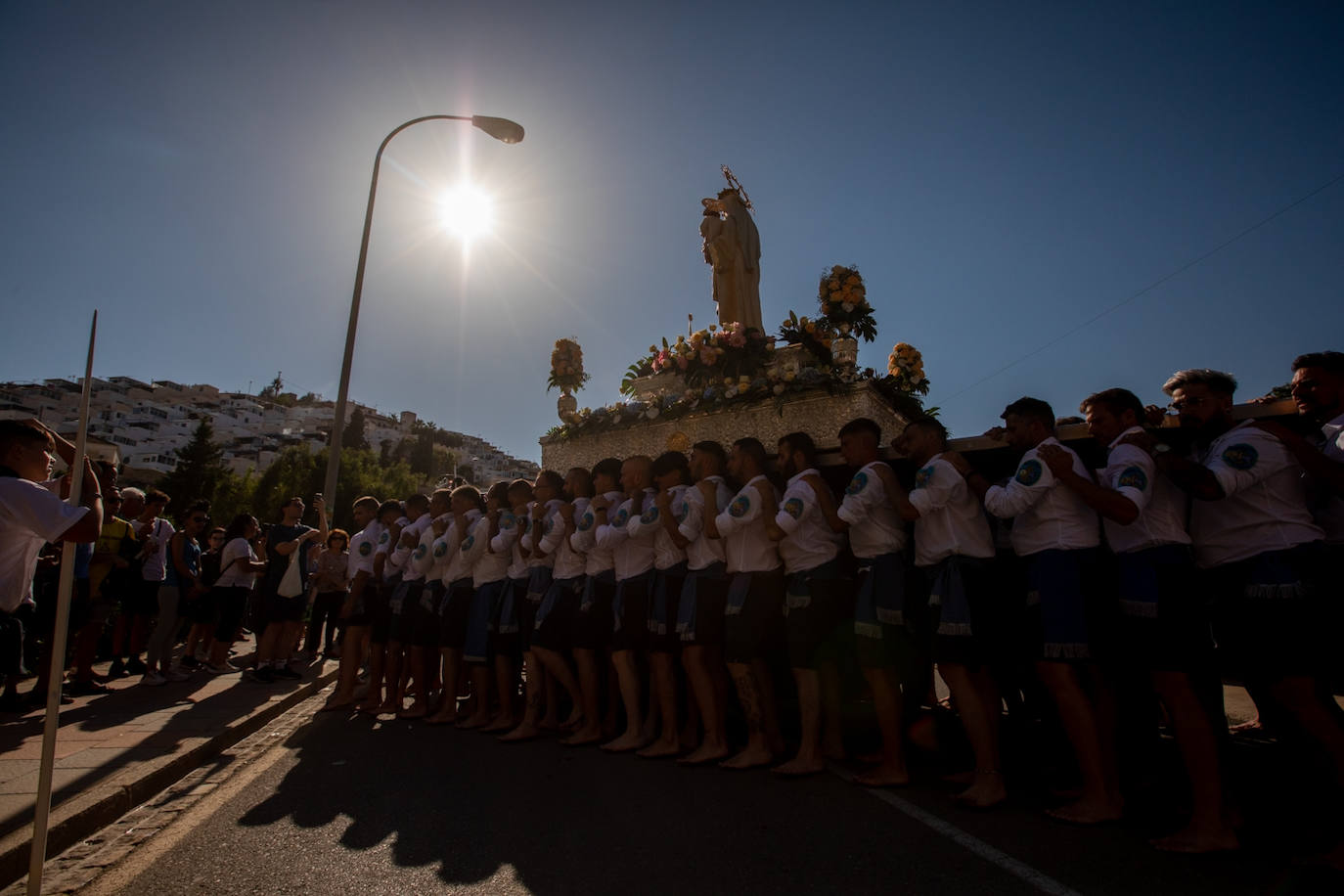 La Virgen del Carmen de Almuñéca, con el Barrio de Los Marinos al fondo, enfila la playa de San Cristóbal tras salir de la capilla.