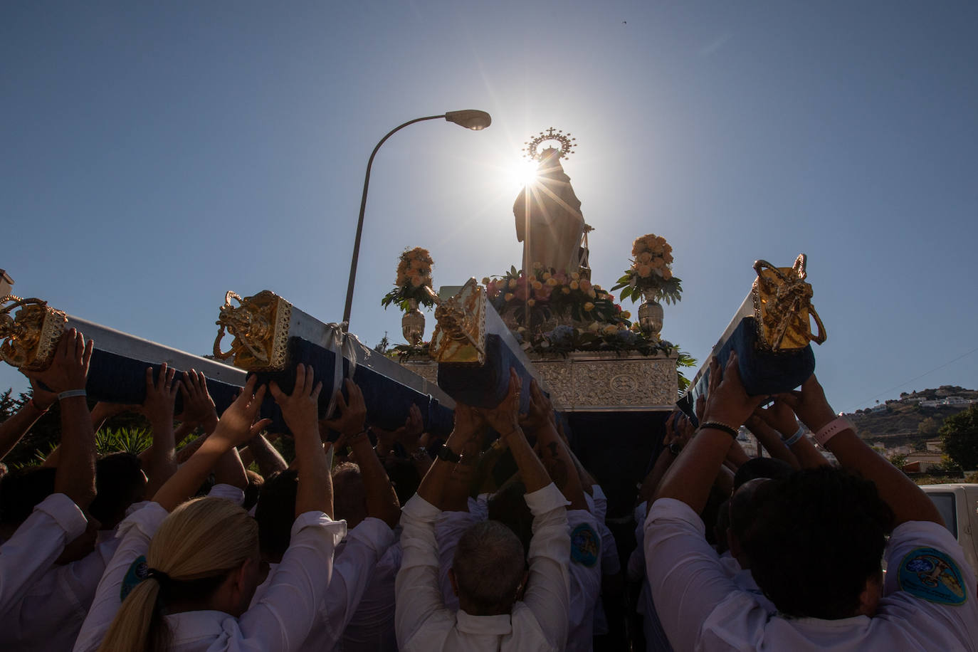 La Virgen del Carmen de Almuñéca, con el Barrio de Los Marinos al fondo, enfila la playa de San Cristóbal tras salir de la capilla.