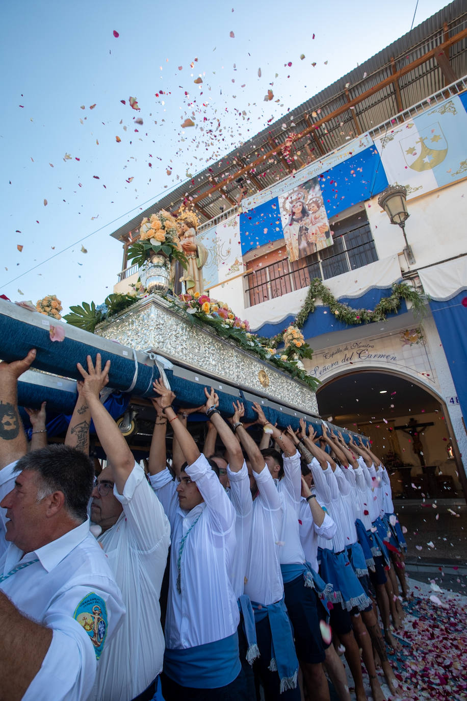 La Virgen del Carmen de Almuñéca, con el Barrio de Los Marinos al fondo, enfila la playa de San Cristóbal tras salir de la capilla.