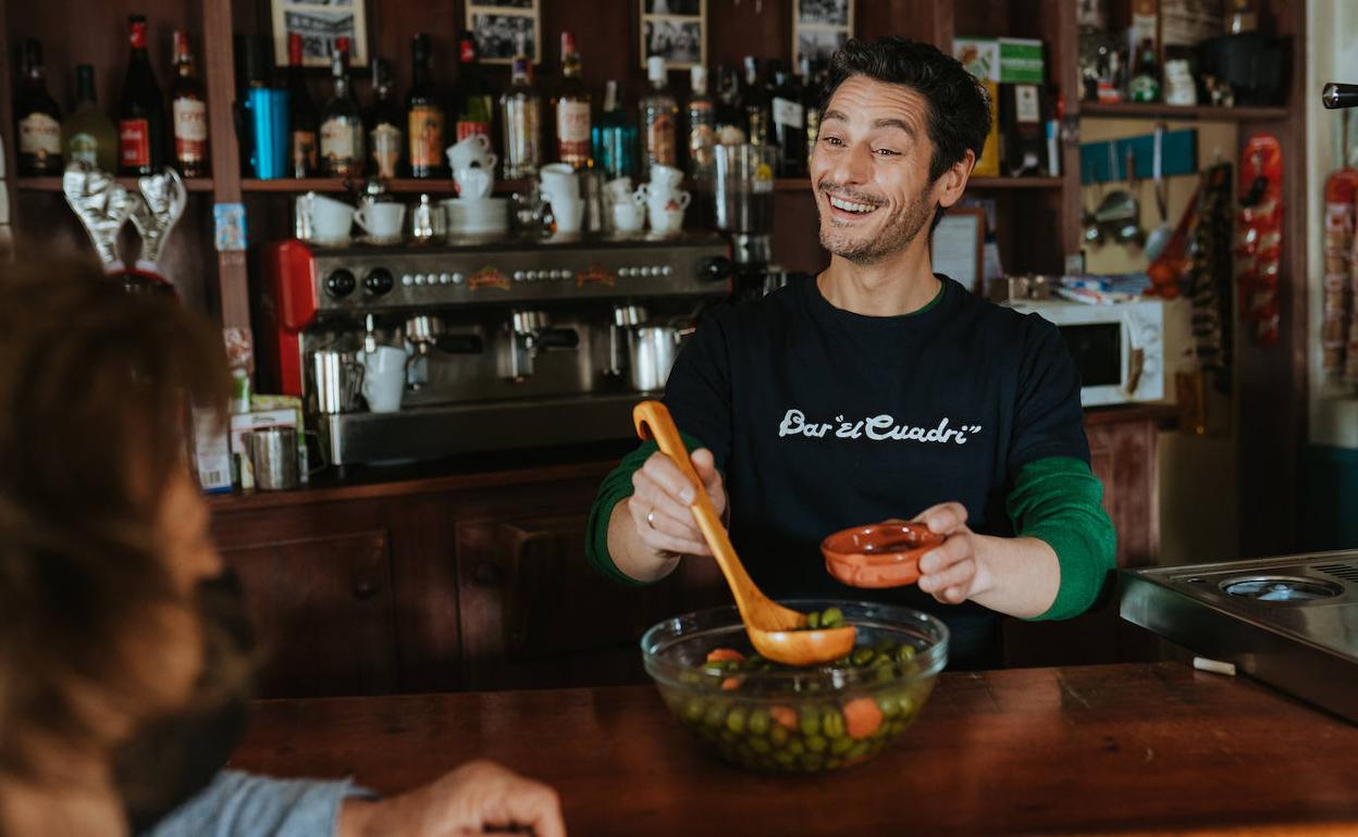 Antonio Pagudo, dueño de un bar en 'Héroes de barrio', sirve unas aceitunas en una escena de la película. 