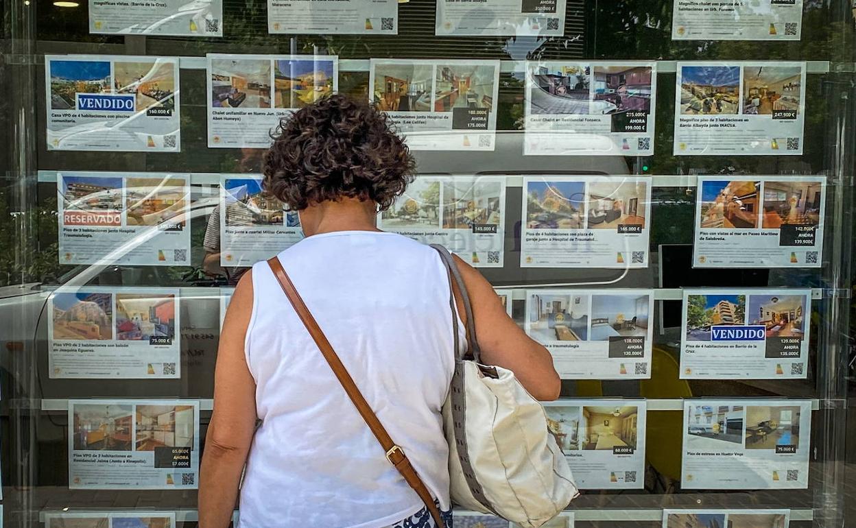 Una granadina observa ofertas de vivienda en el escaparate de una inmobiliaria 