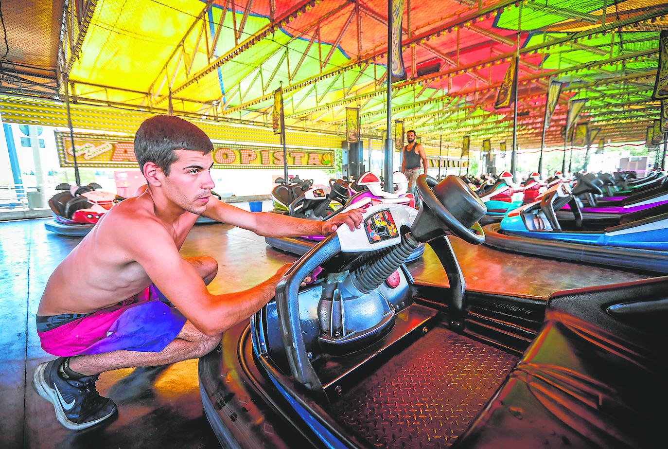 Un jóven limpia los coches de choque en el Zaidín. 