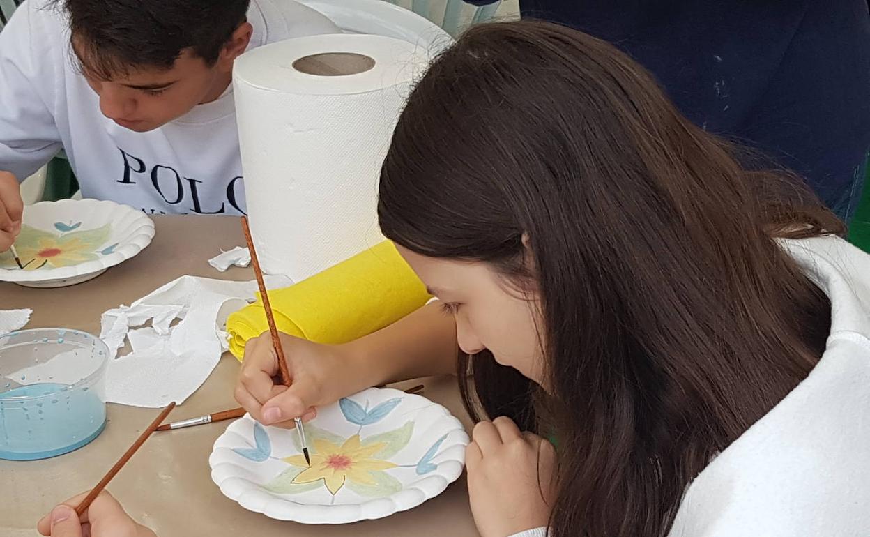 Una joven pinta un plato de cerámica en la feria. 