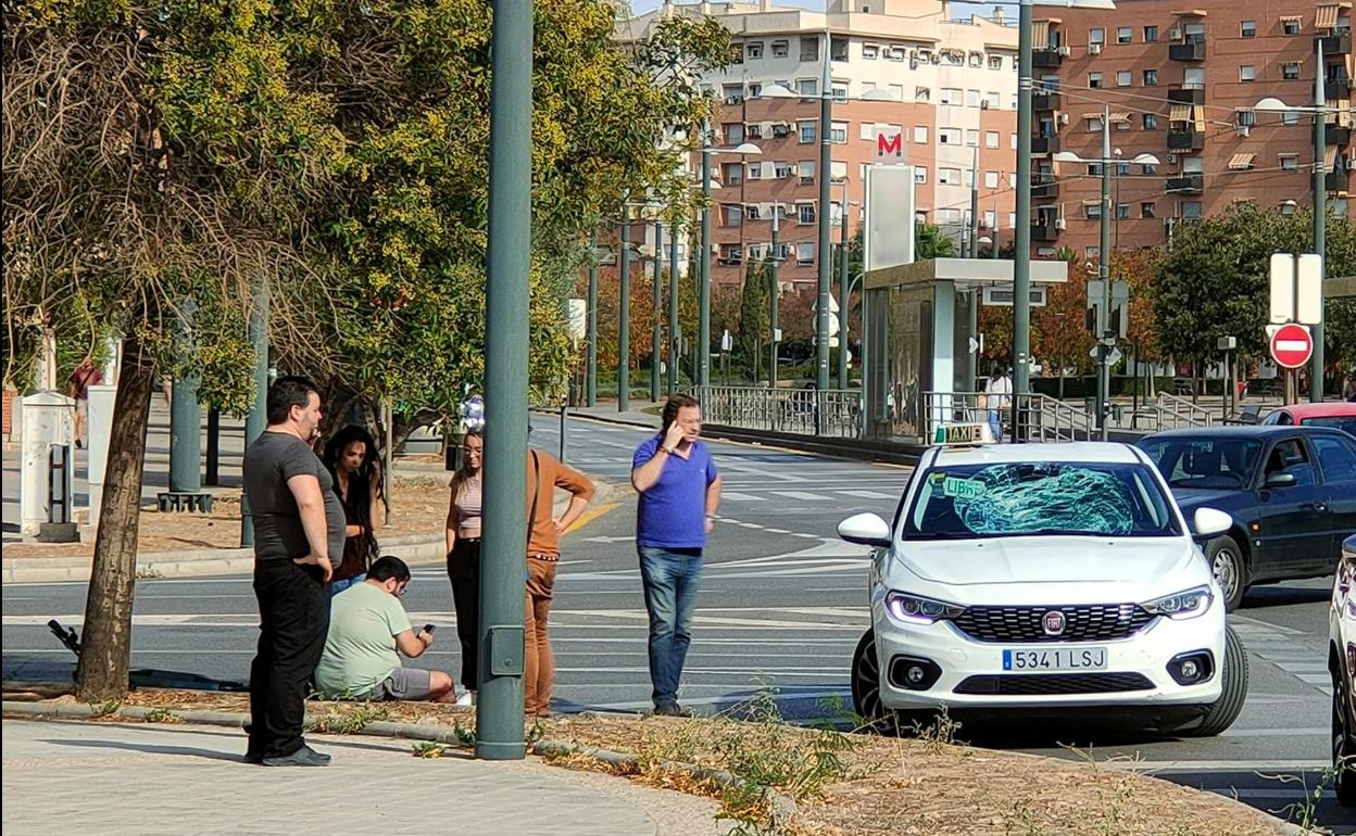 El herido sentado en la acera junto al taxi, con la luna destrozada.